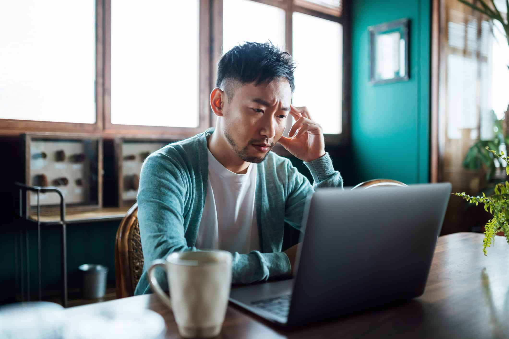 confused man who is about to file for bankruptcy on a laptop computer