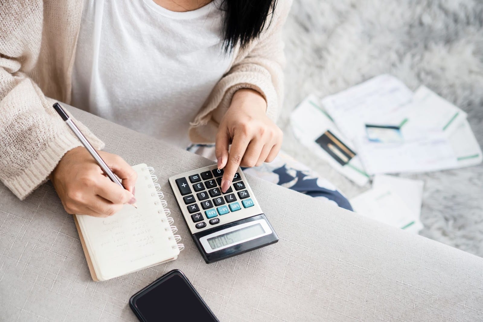 woman budgetting expenses using a calculator and a notebook
